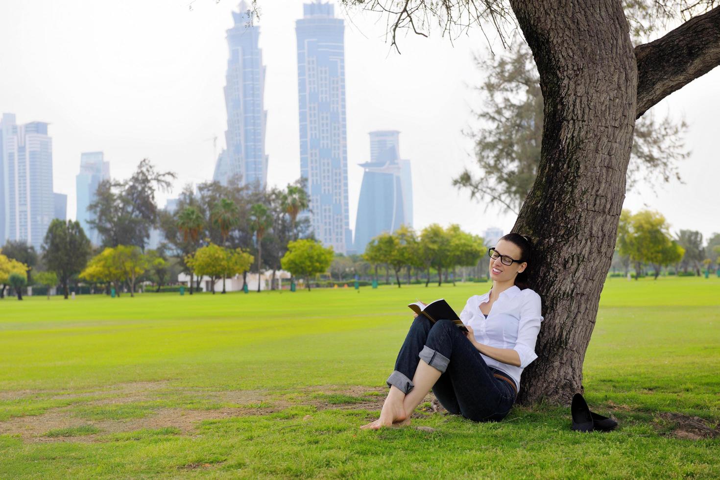 jonge vrouw die een boek in het park leest foto