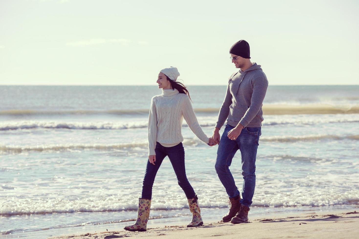 liefhebbend jong paar Aan een strand Bij herfst zonnig dag foto