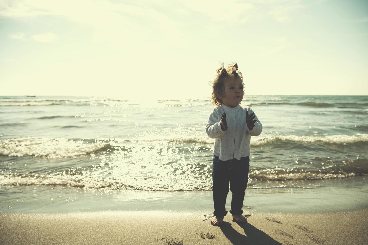 schattig weinig meisje Bij herfst strand foto