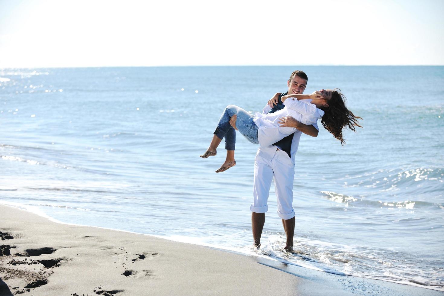 gelukkig jong paar hebben pret Bij mooi strand foto