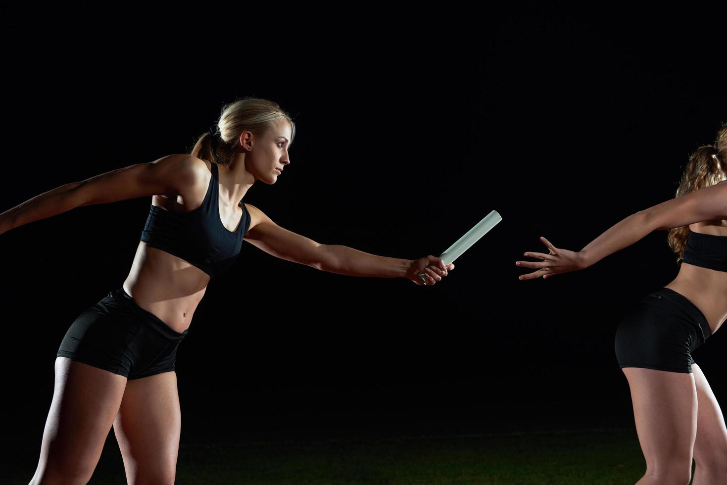 atletisch hardlopers voorbijgaan stok in relais ras foto