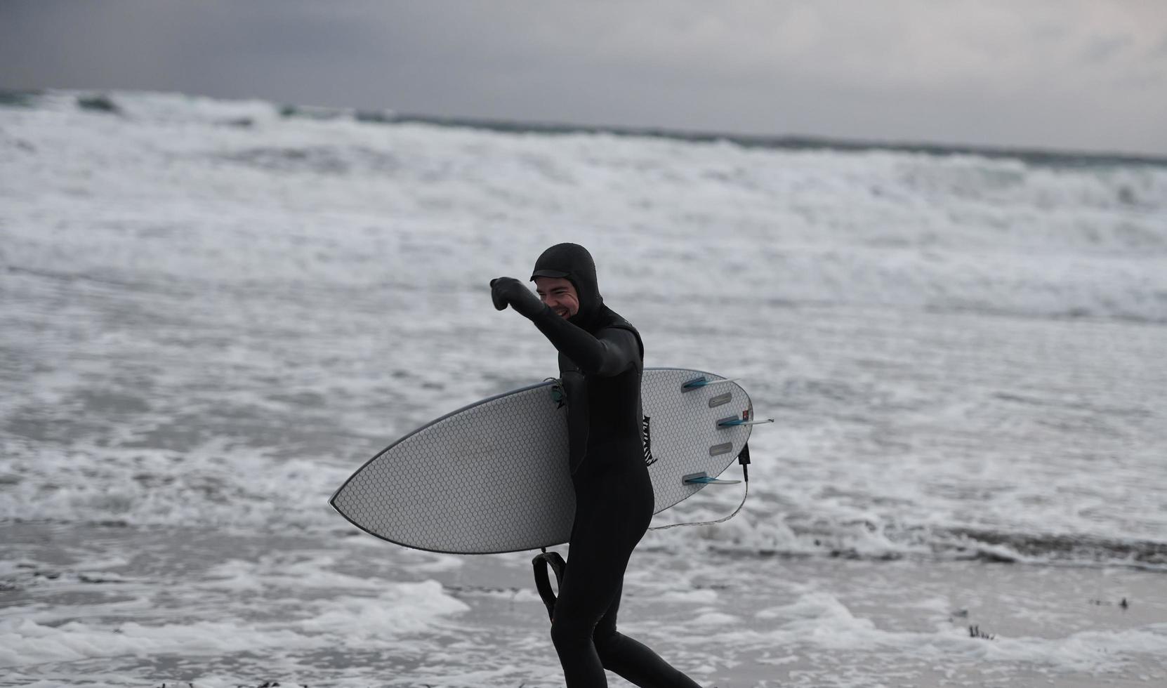 arctisch surfer gaan door strand na surfing foto