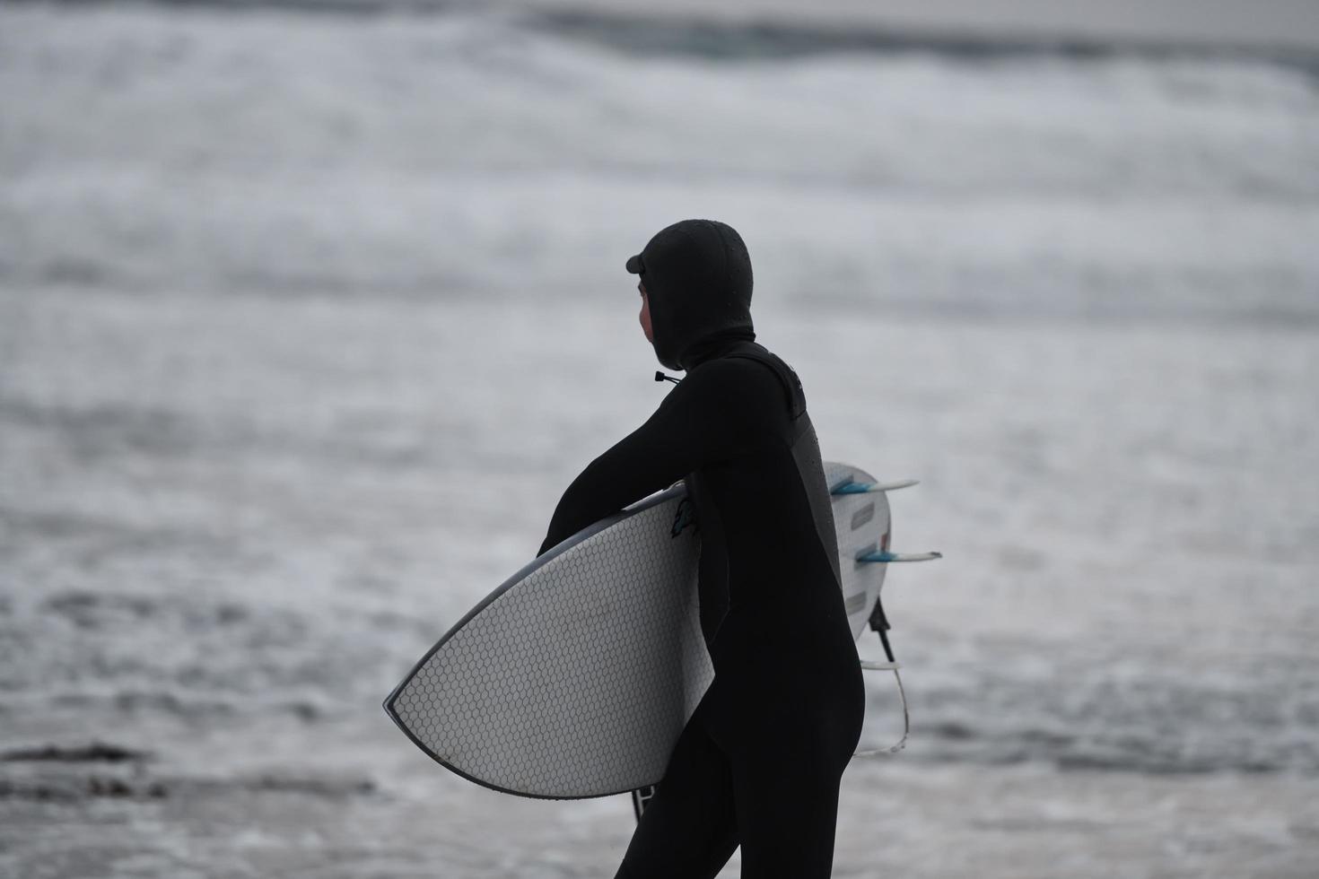 arctisch surfer gaan door strand na surfing foto