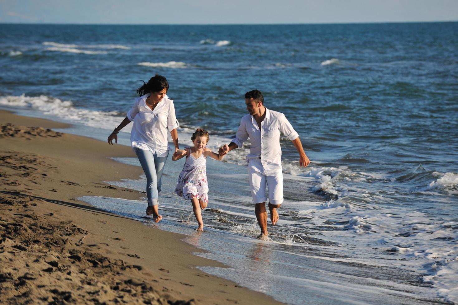 gelukkig jong familie hebben pret Aan strand foto