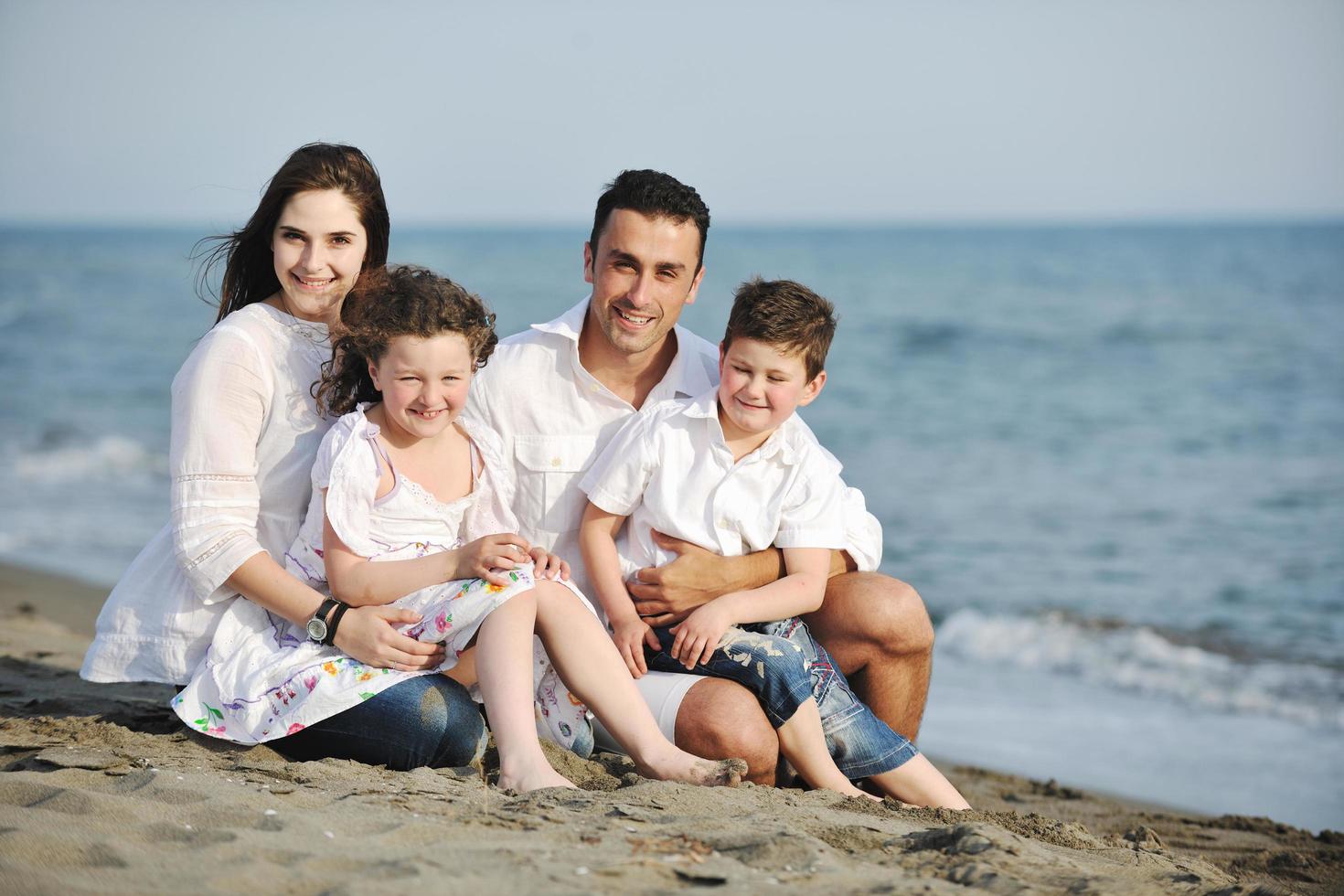 gelukkig jong familie hebben pret Aan strand foto