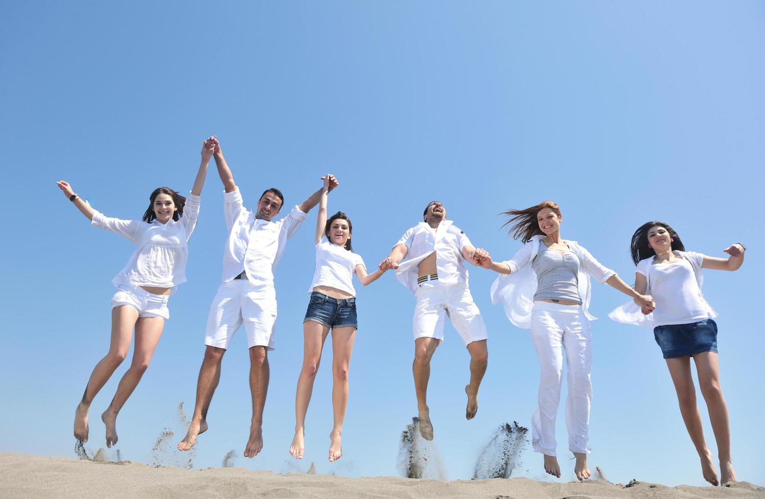 gelukkig mensen groep hebben pret en rennen Aan strand foto