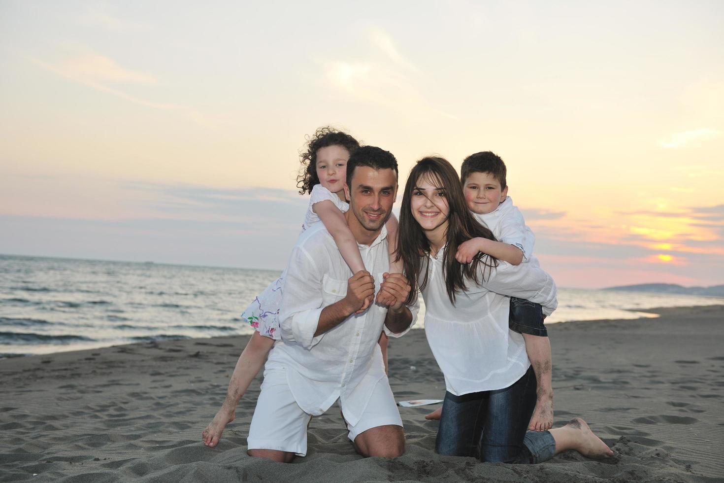 gelukkig jong familie hebben pret Aan strand foto