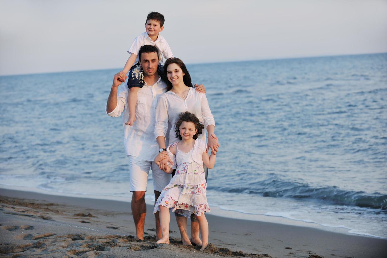 gelukkig jong familie hebben pret Aan strand foto