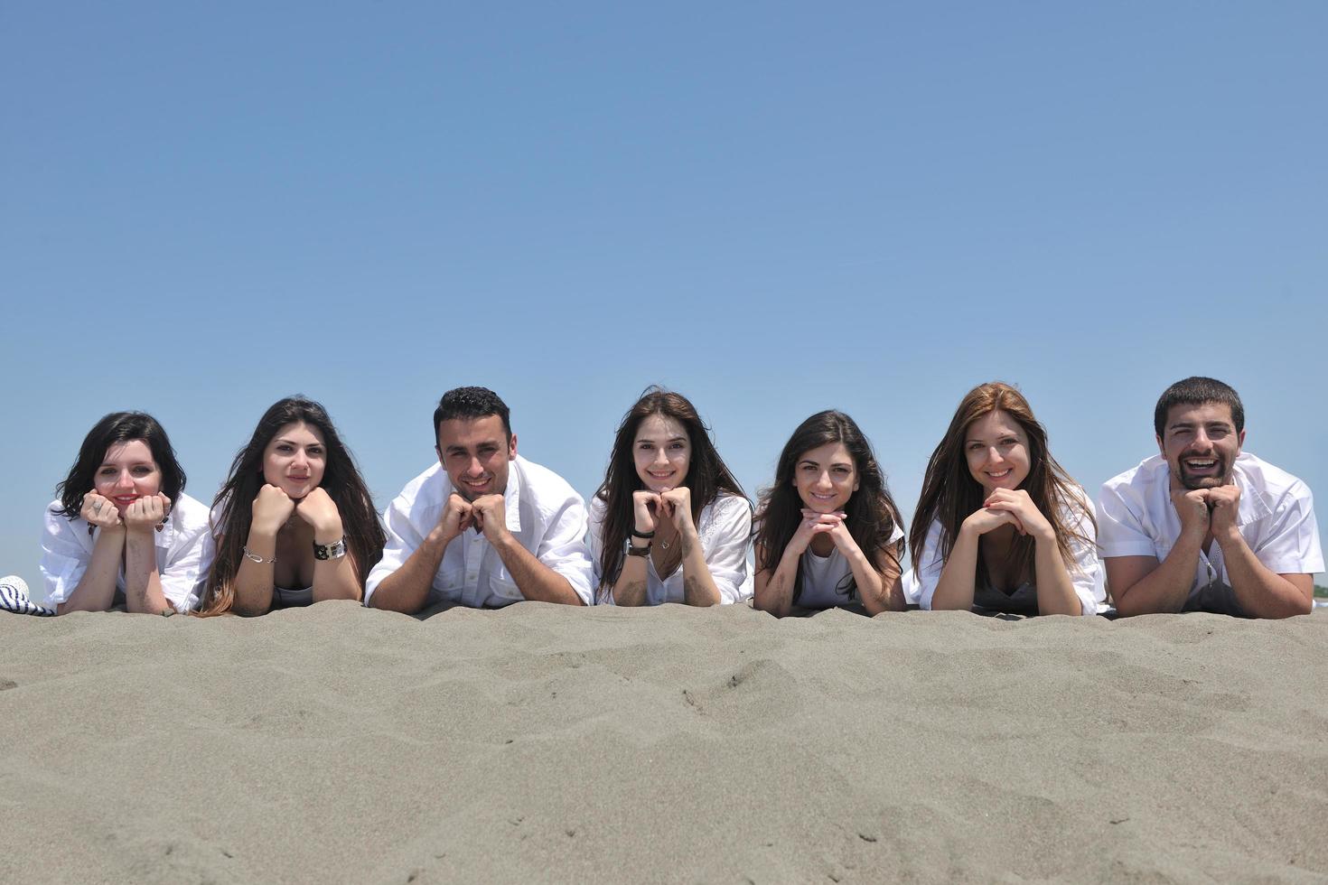 groep van gelukkig jong mensen in hebben pret Bij strand foto