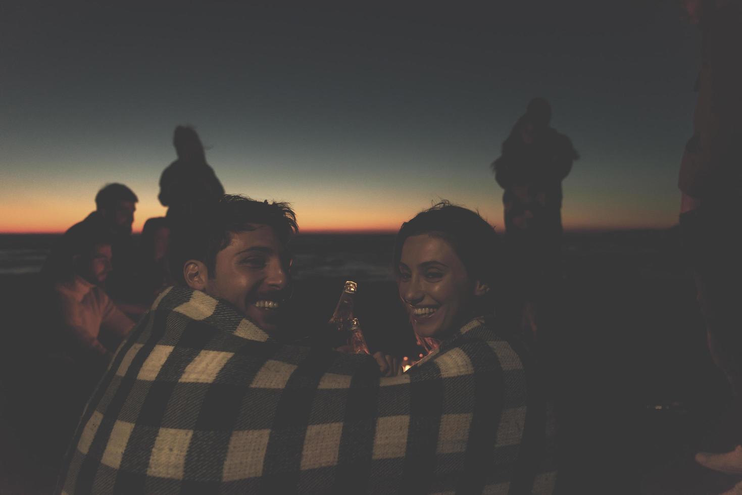 paar genieten van met vrienden Bij zonsondergang Aan de strand foto