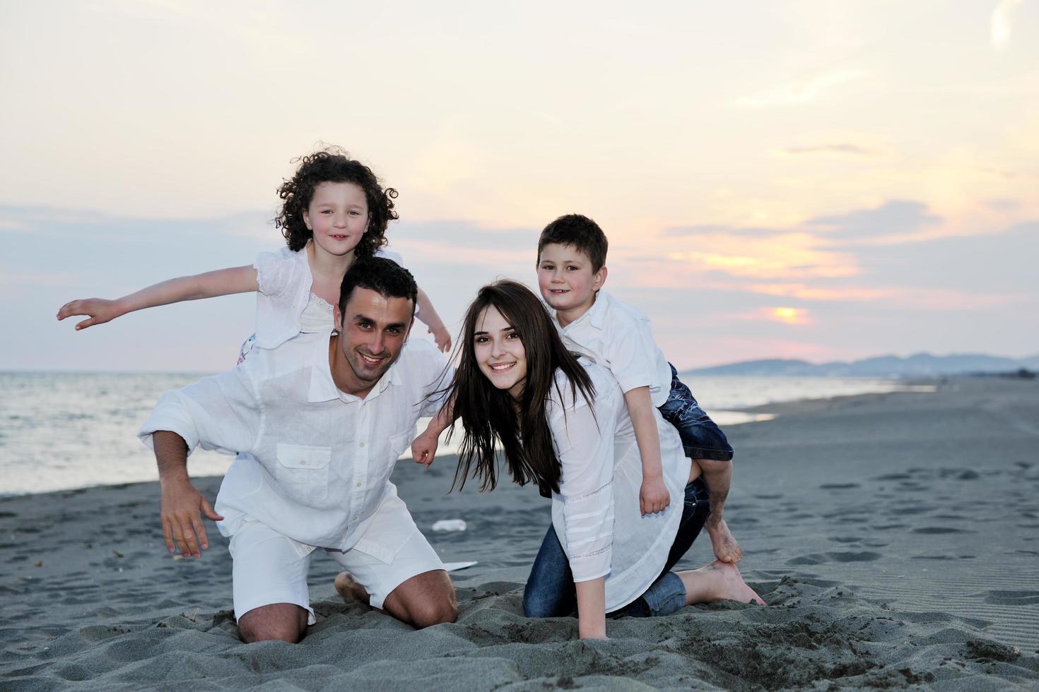 gelukkig jong familie hebben pret Aan strand foto