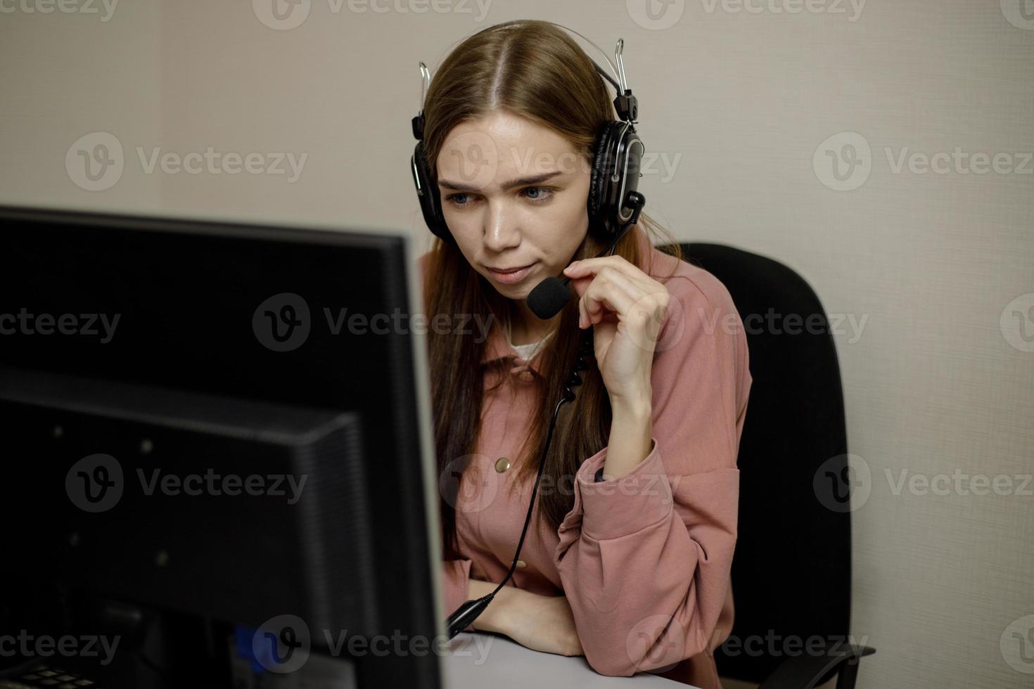 een echt telefoontje centrum operator is pratend naar een cliënt terwijl op zoek Bij een computer scherm in detailopname. foto