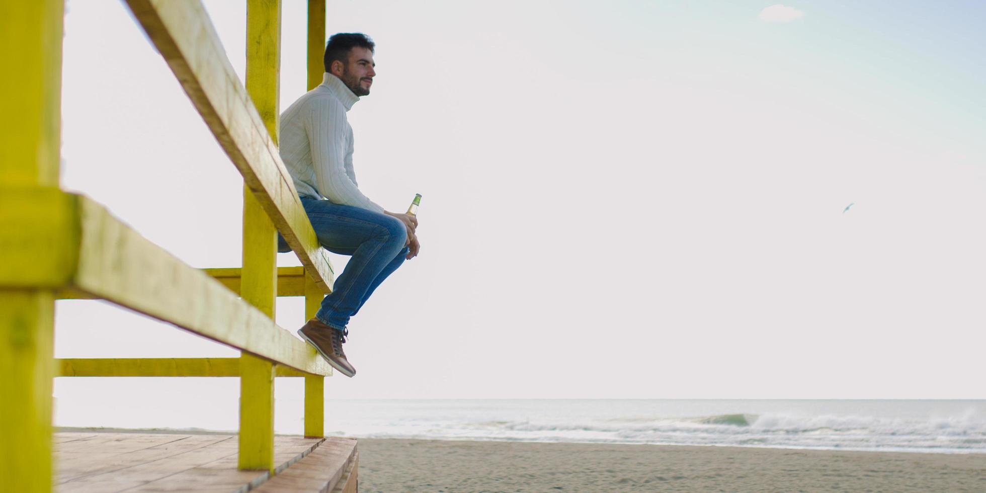 Mens drinken bier Bij de strand foto