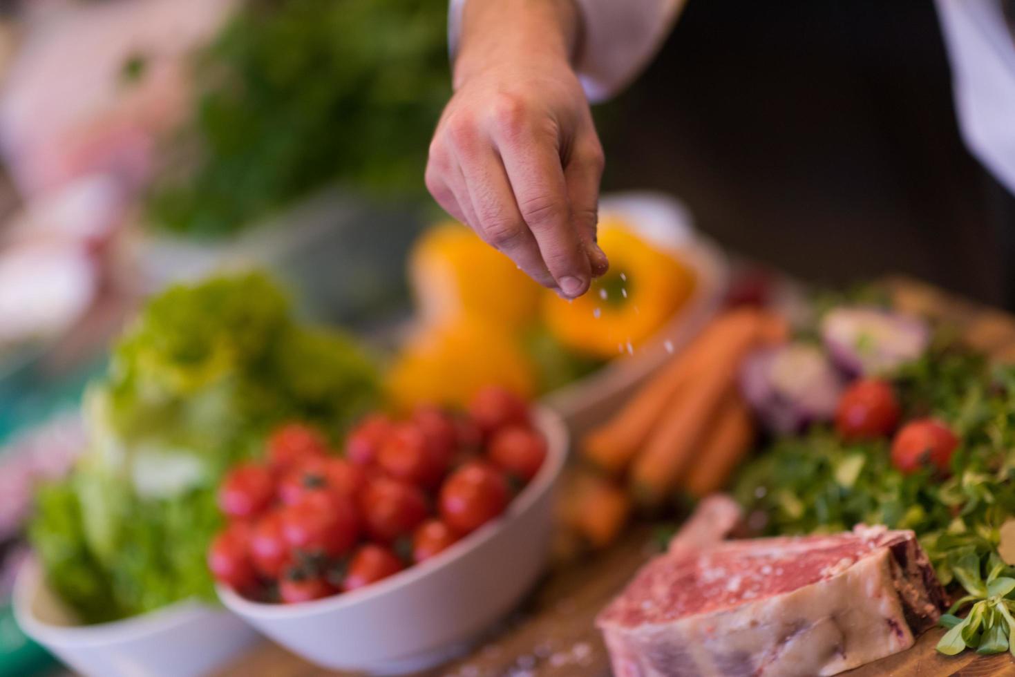 chef zetten zout Aan sappig plak van rauw steak foto