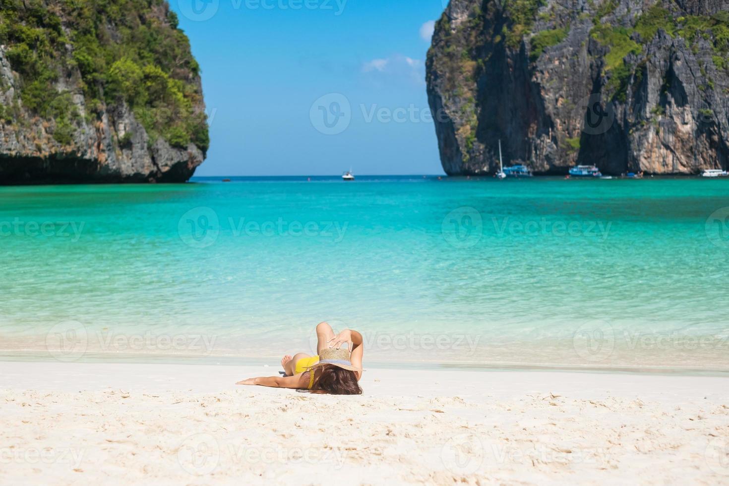 vrouw toerist in gele zwembroek en hoed, gelukkige reiziger zonnebaden op maya bay beach op phi phi island, krabi, thailand. mijlpaal, bestemming Zuidoost-Azië reizen, vakantie en vakantieconcept foto