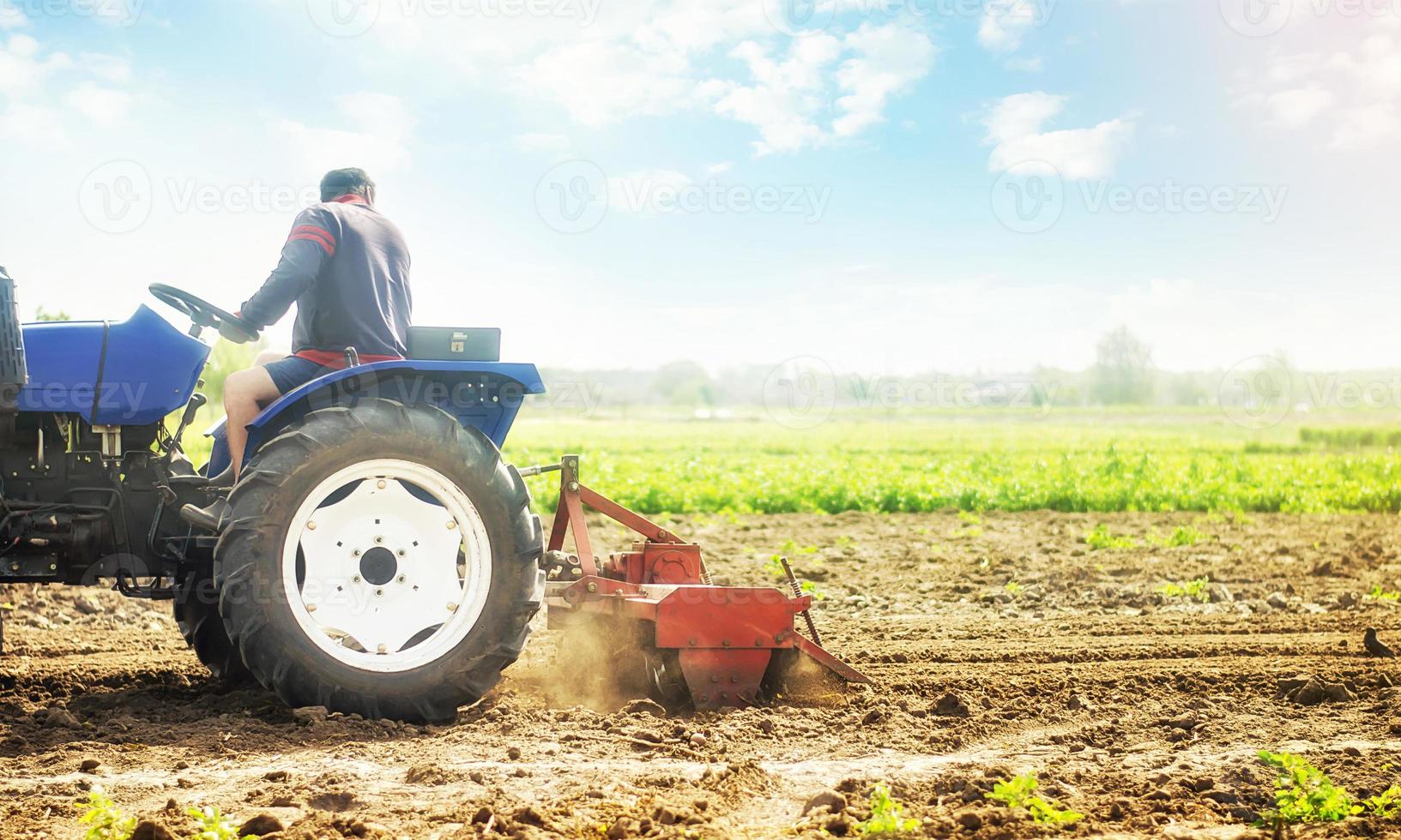 boer Aan een trekker cultiveert een boerderij veld. werk Aan voorbereidingen treffen de bodem voor een nieuw zaaien van zaden van agrarisch gewassen. bodem frezen, afbrokkelen en mengen. slijpen en losmaken. landbouw foto