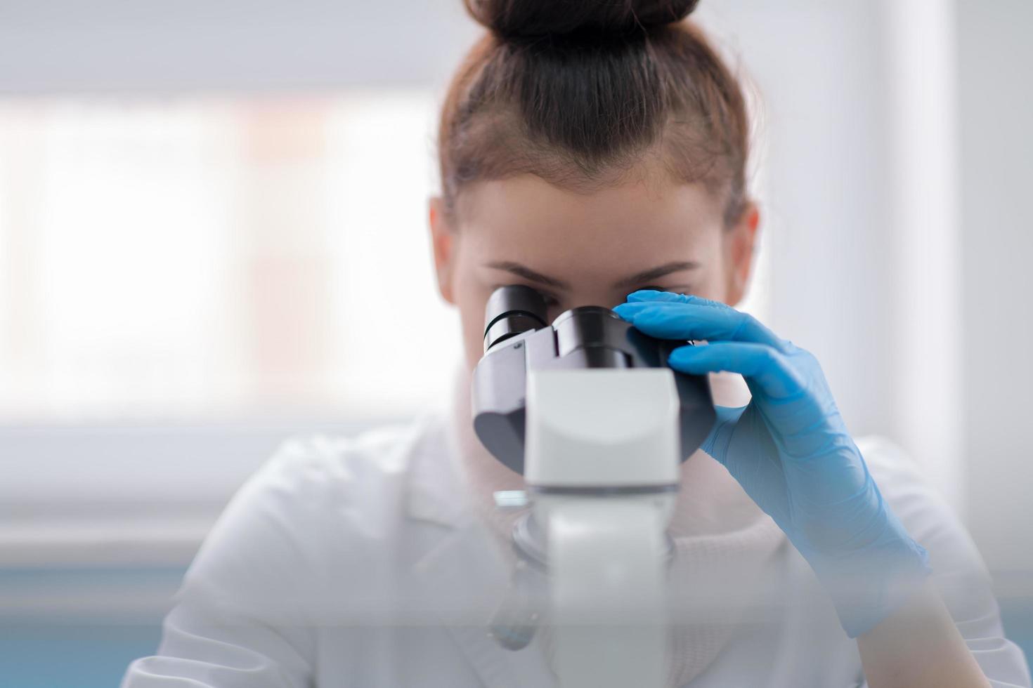 vrouw leerling wetenschapper op zoek door een microscoop foto