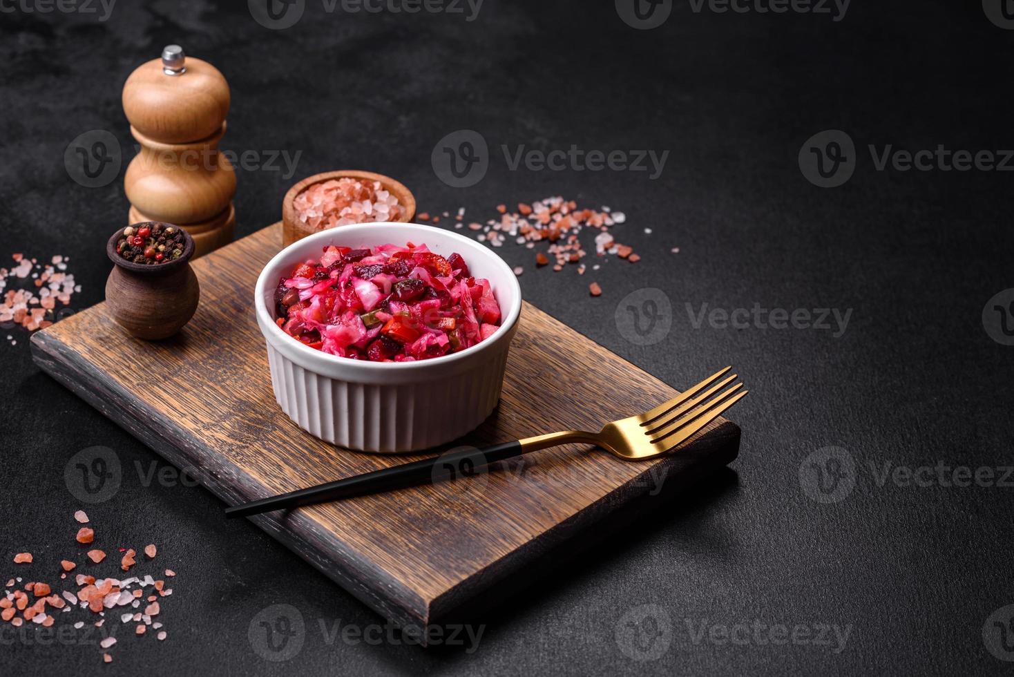traditioneel oekraïens rode biet salade vinaigrette Aan een wit bord Aan een zwart beton of leisteen achtergrond foto