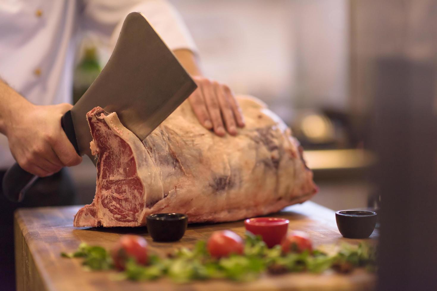 chef snijdend groot stuk van rundvlees foto