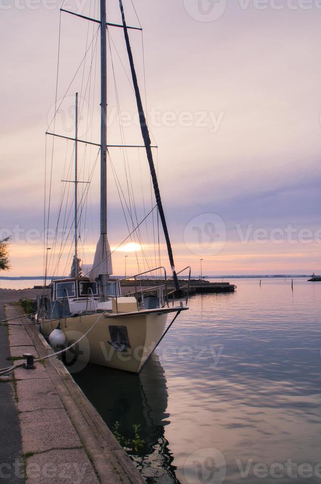 het zeilen schip in de haven van meer vaetern Bij zonsondergang. vuurtoren in de achtergrond foto