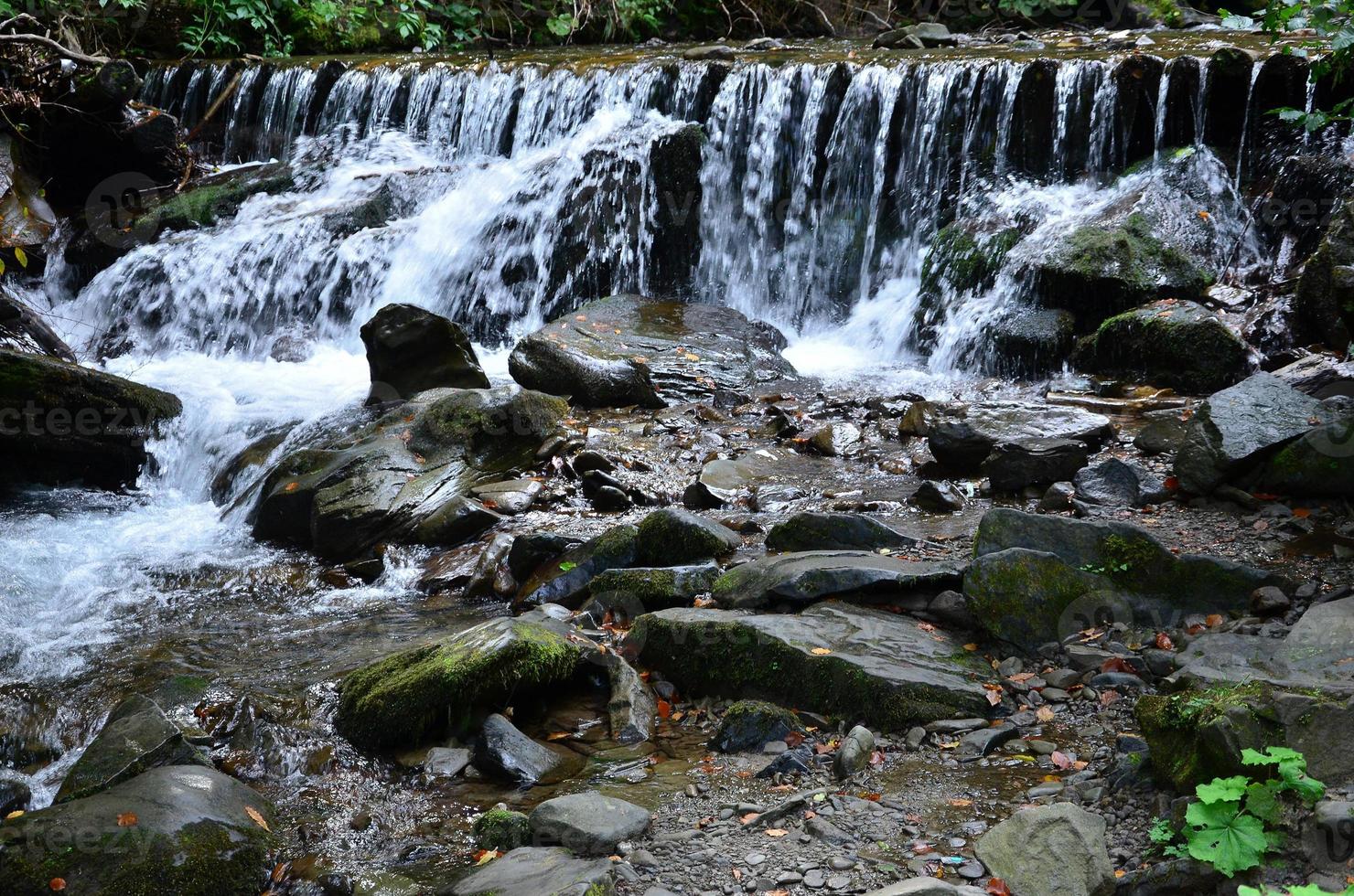 detailopname beeld van een klein wild waterval in de het formulier van kort streams van water tussen berg stenen foto