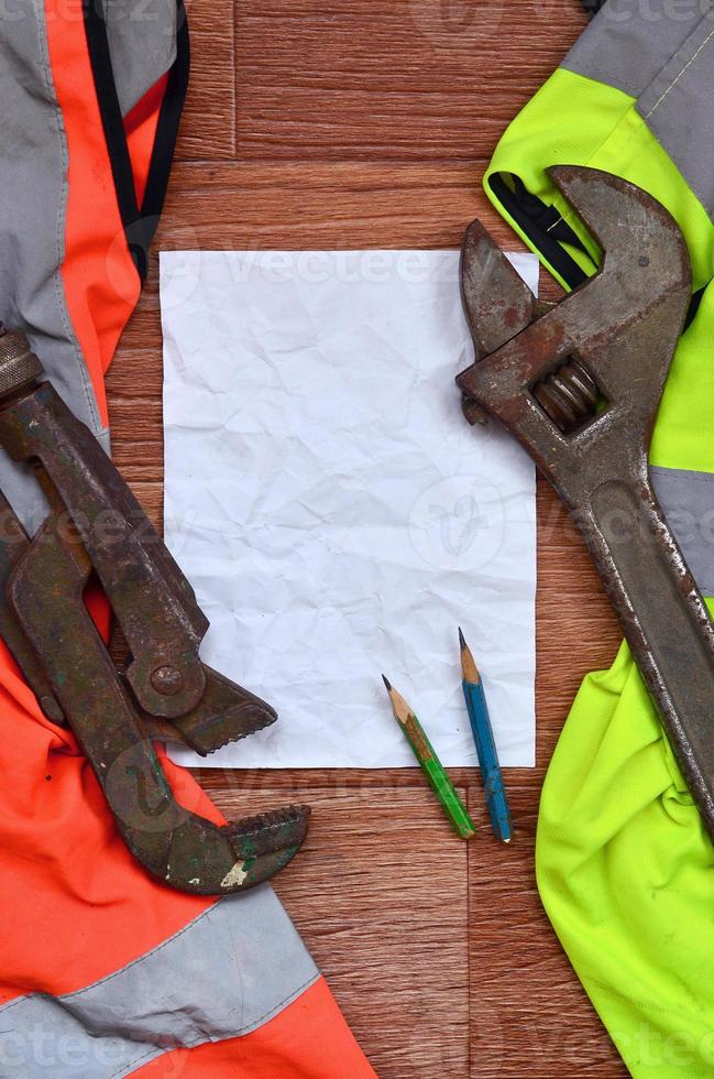 een verfrommeld vel van papier met twee potloden omringd door groen en oranje werken uniformen en verstelbaar sleutels foto