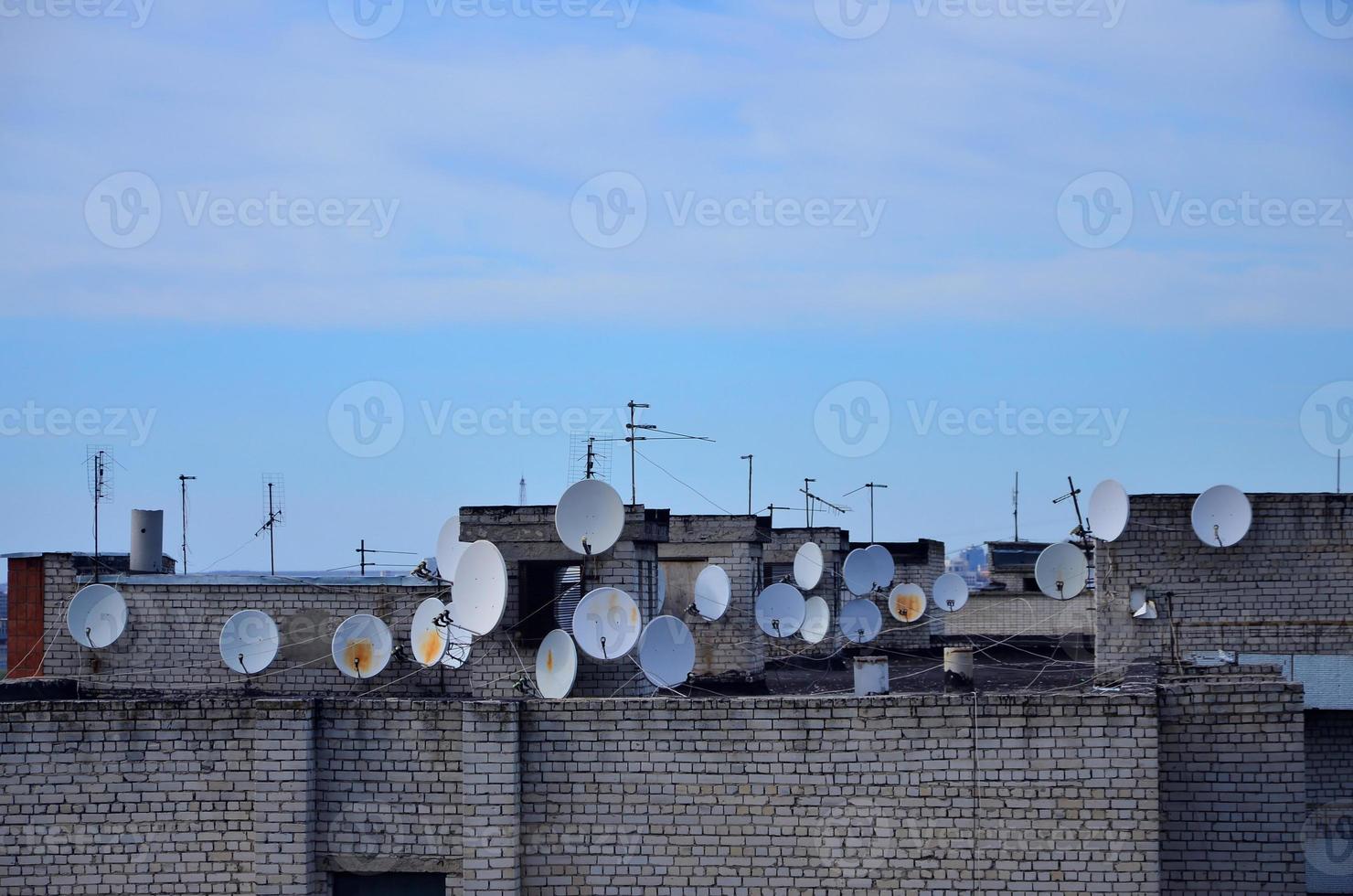 een veel van satelliet televisie antennes Aan de op het dak onder een blauw lucht foto