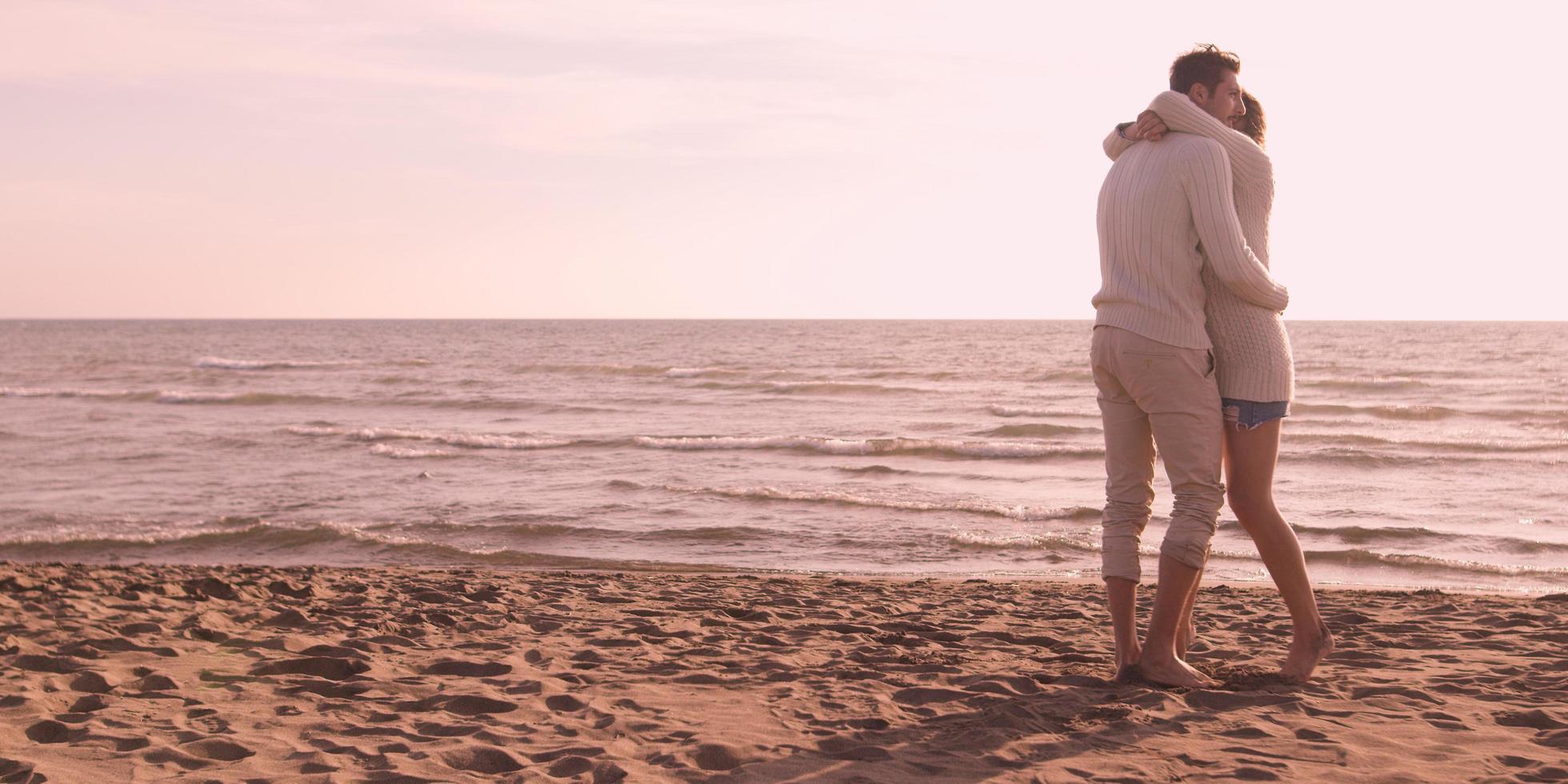 liefhebbend jong paar Aan een strand Bij herfst Aan zonnig dag foto