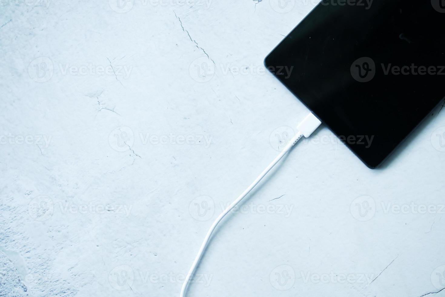 opladen s digitale tablet met een kabel op witte achtergrond foto