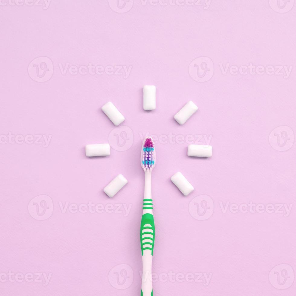 tandenborstel en kauwen tandvlees liggen Aan een pastel roze achtergrond foto