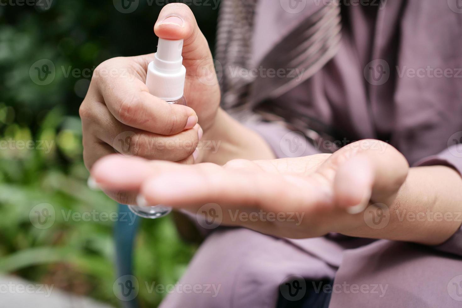 jong Dames hand- gebruik makend van hand- ontsmettingsmiddel verstuiven buitenshuis foto