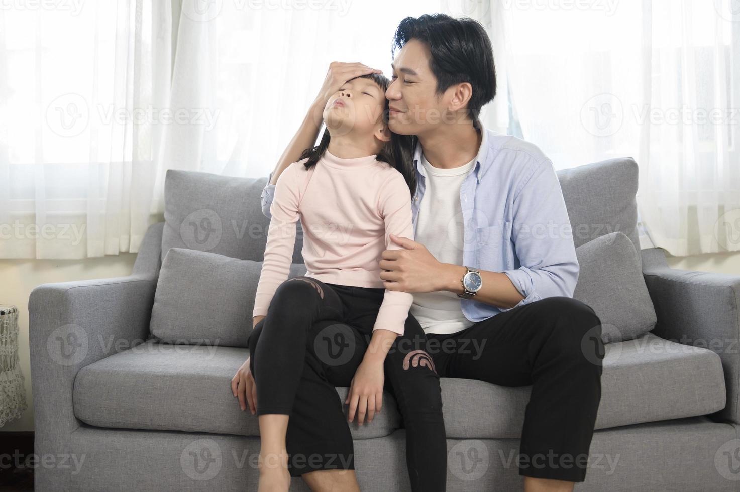 portret van Aziatisch vader en dochter zittend Aan bankstel in de leven kamer foto