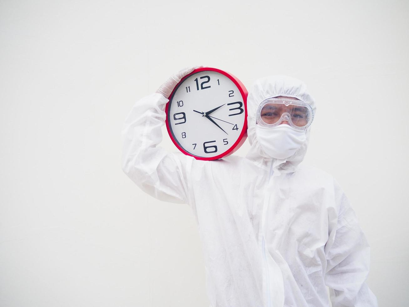 portret van dokter of wetenschapper in ppe suite uniform Holding rood alarm klok en op zoek Bij de camera in divers gebaren. covid-19 concept geïsoleerd wit achtergrond foto