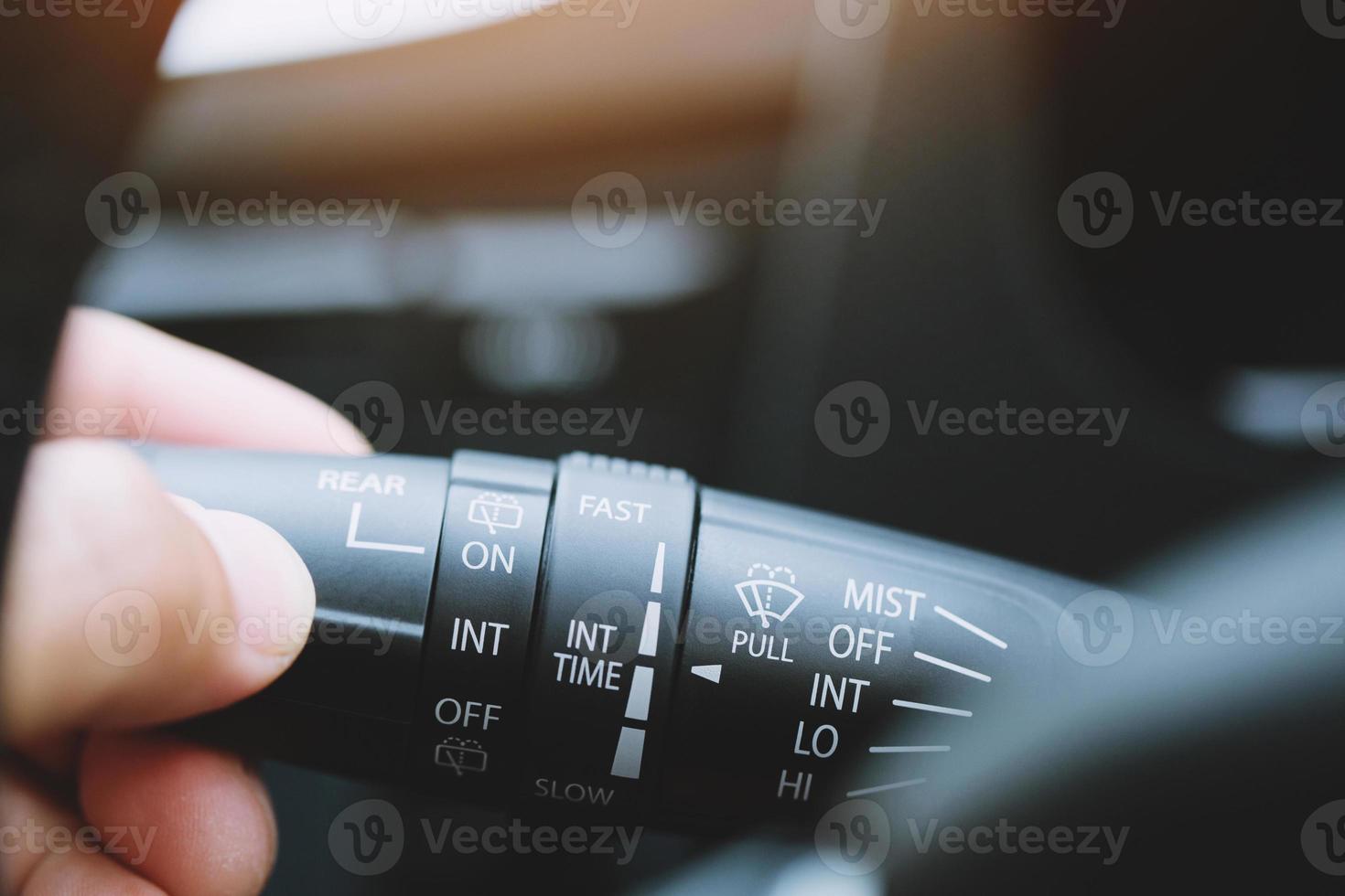 close-up hand afstellen regen ruitenwisser knop controle stick schakelaar snelheid van scherm voorste auto. verstelbaar wisserblad verwijdert vuil van de voorruit. moderne auto interieur detail. foto