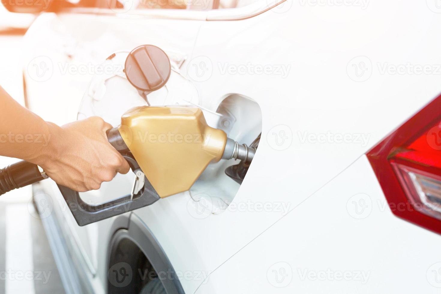 Mens omgaan met bijvullen de auto met brandstof Bij de bijtanken station foto