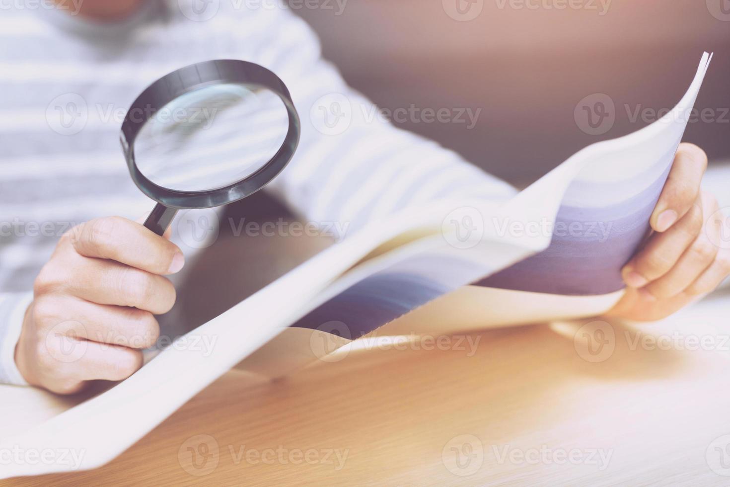 Mens op zoek door een vergroten glas naar documenten notebook. foto