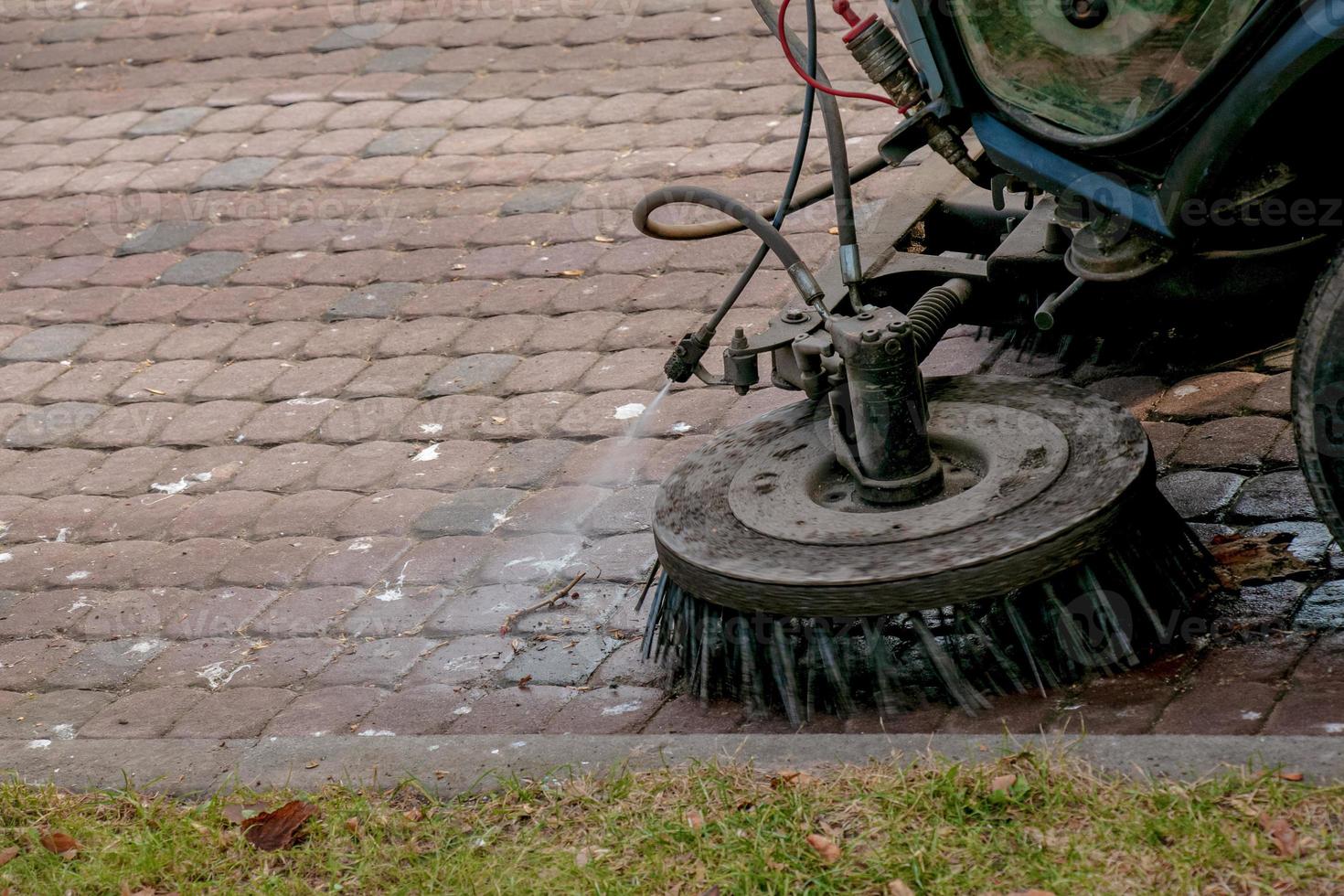 de gemeentelijk onderhoud voert seizoensgebonden werk in de park. de veger picks omhoog een veel van brokstukken. de borstels vegen de asfalt foto