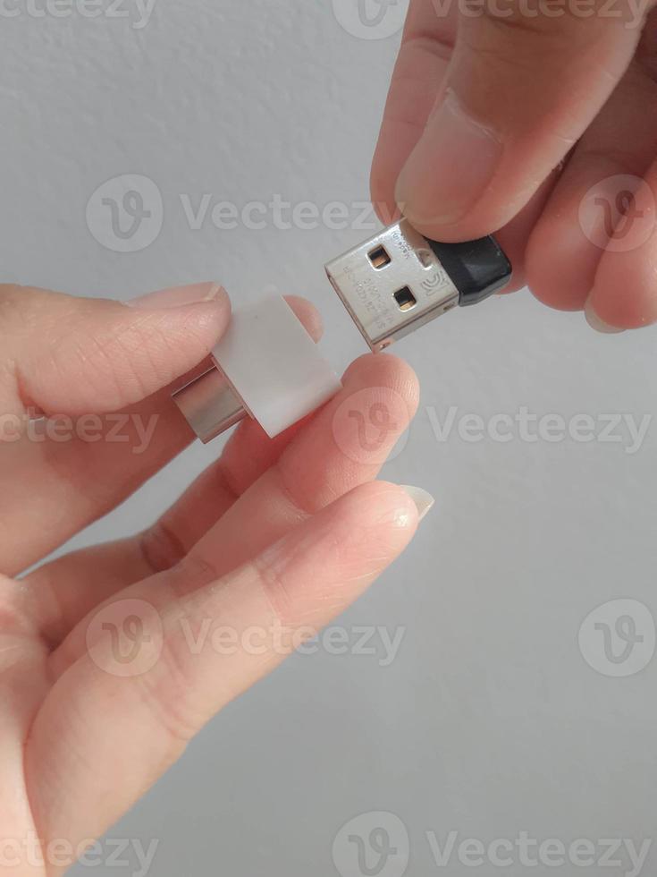 een hand- is proberen naar insert een klein fles schijf in een adapter USB type c naar USB 3.0 type-c adapter otg foto