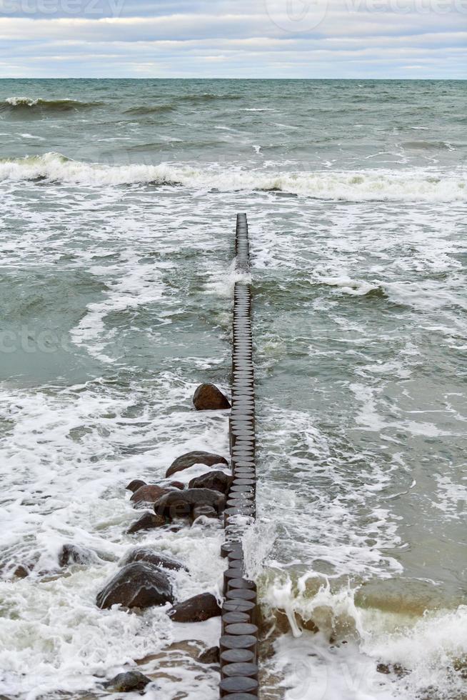 uitzicht op blauwe zee met schuimende golven en houten golfbrekers foto