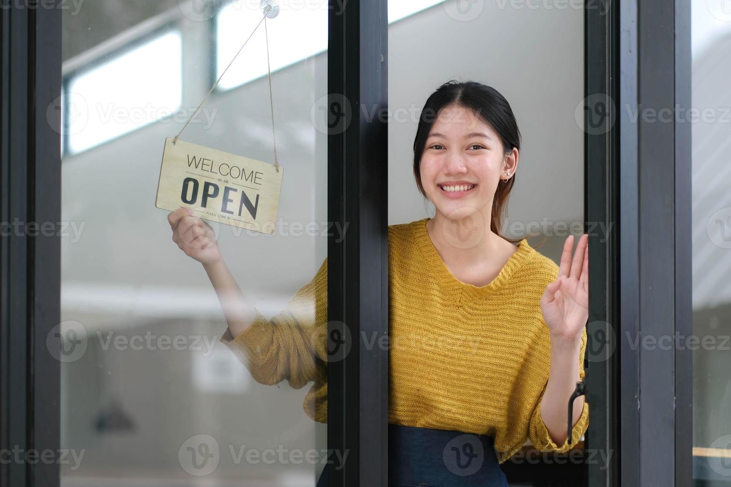 jong Azië manager meisje veranderen een teken van Gesloten naar Open teken Aan deur cafe op zoek buiten aan het wachten voor klanten na lockdown. eigenaar klein bedrijf, voedsel en drankje, bedrijf heropenen opnieuw concept foto