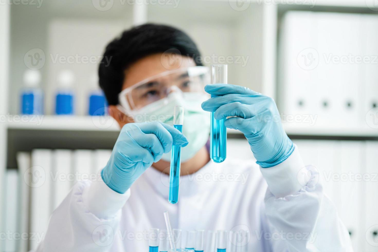 een mannetje wetenschapper, een specialist in een laboratorium werken met test buizen. wetenschapper. chemicus. wetenschap technologie concept. medisch Onderzoek laboratorium. een mannetje wetenschapper analyses blauw vloeistof biochemie. foto