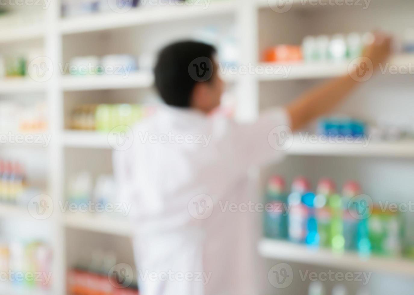 vervagen apotheker die medicijnen van de plank in de apotheek neemt foto