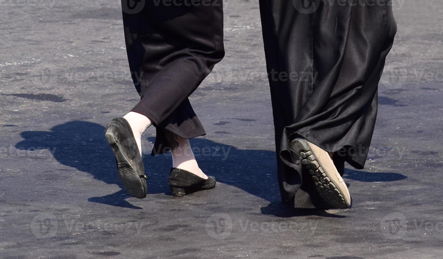 dichtbij omhoog van vrouw voeten wandelen. vrouw in lang rok en zwart schoenen wandelen foto