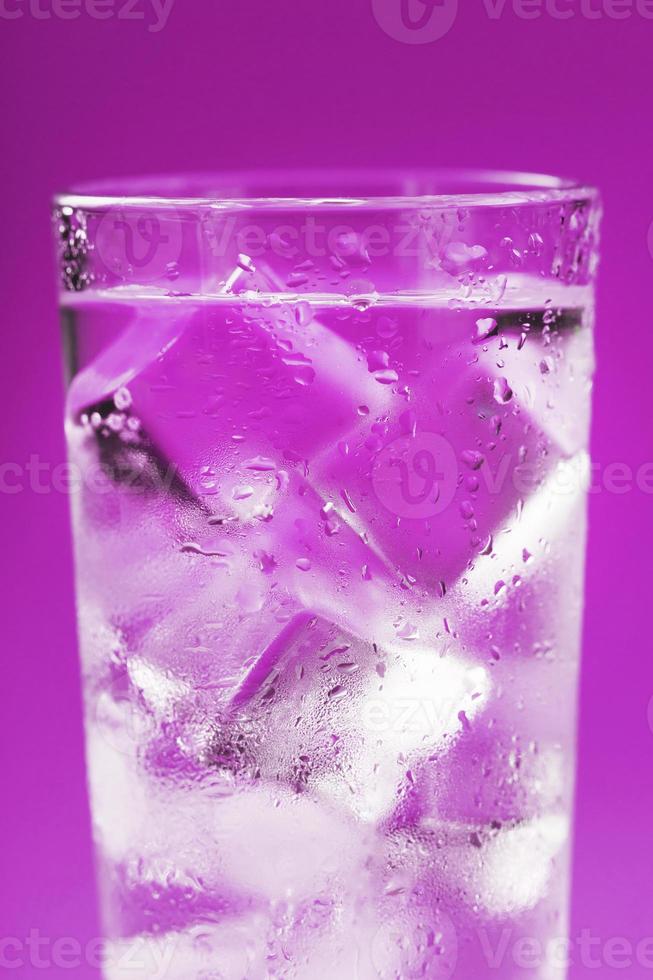 een glas met ijs water en ijs kubussen Aan een blauw achtergrond. foto