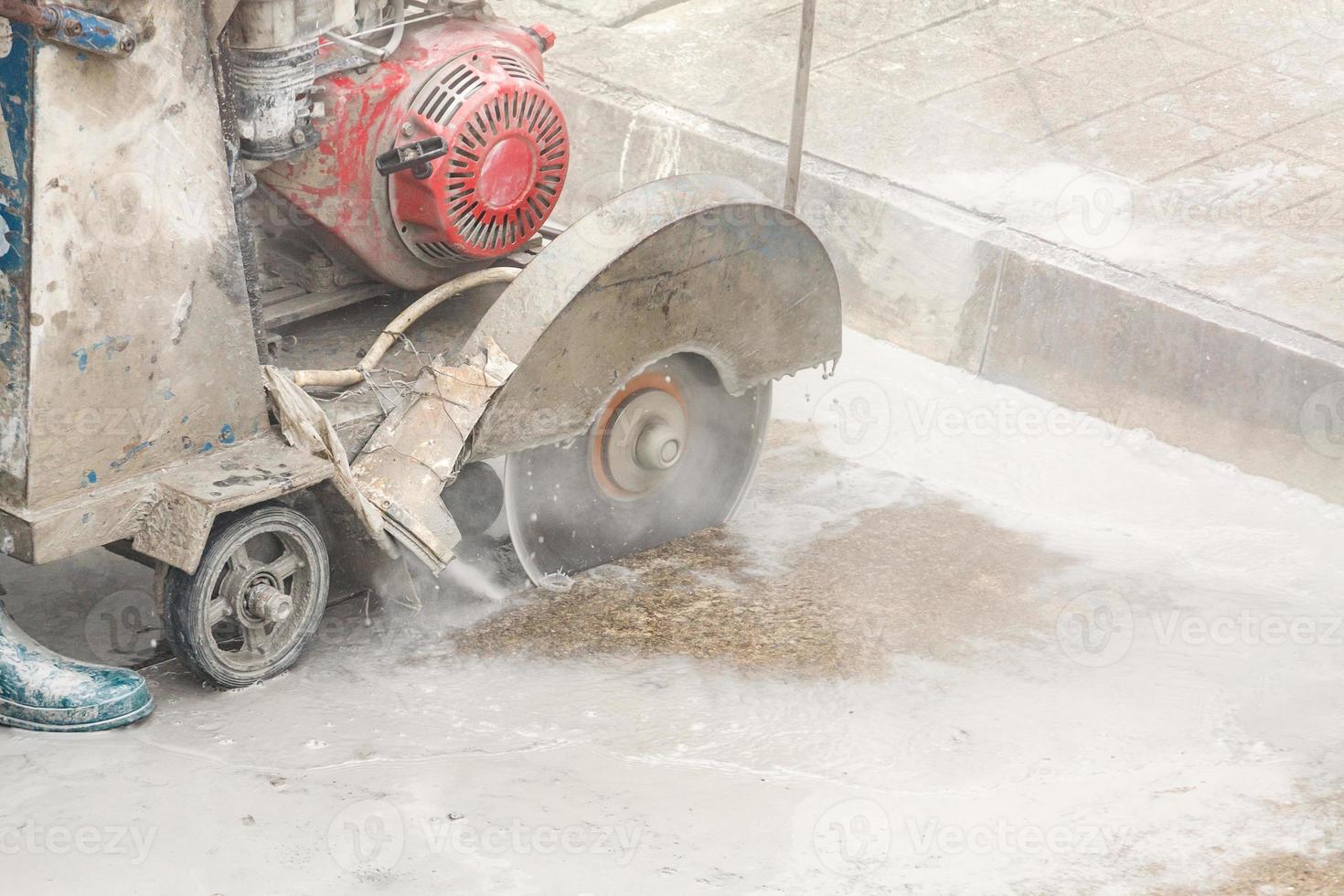 arbeider gebruik makend van diamant zag blad machine snijdend beton weg Bij bouw plaats foto