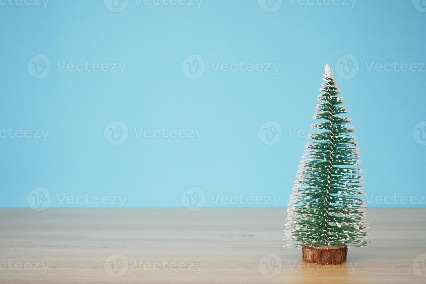 Kerstmis boom Aan hout tafel met blauw muur achtergrond foto