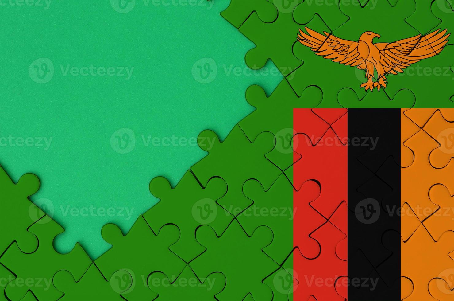 Zambia vlag is afgebeeld Aan een voltooid decoupeerzaag puzzel met vrij groen kopiëren ruimte Aan de links kant foto