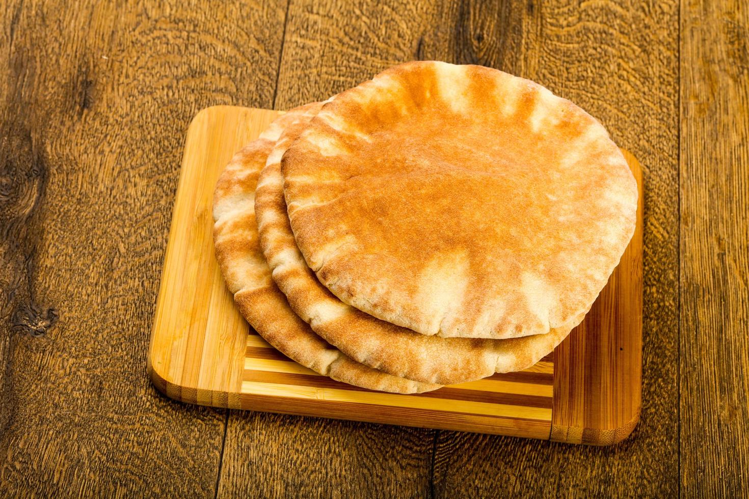 pita brood Aan houten bord en houten achtergrond foto
