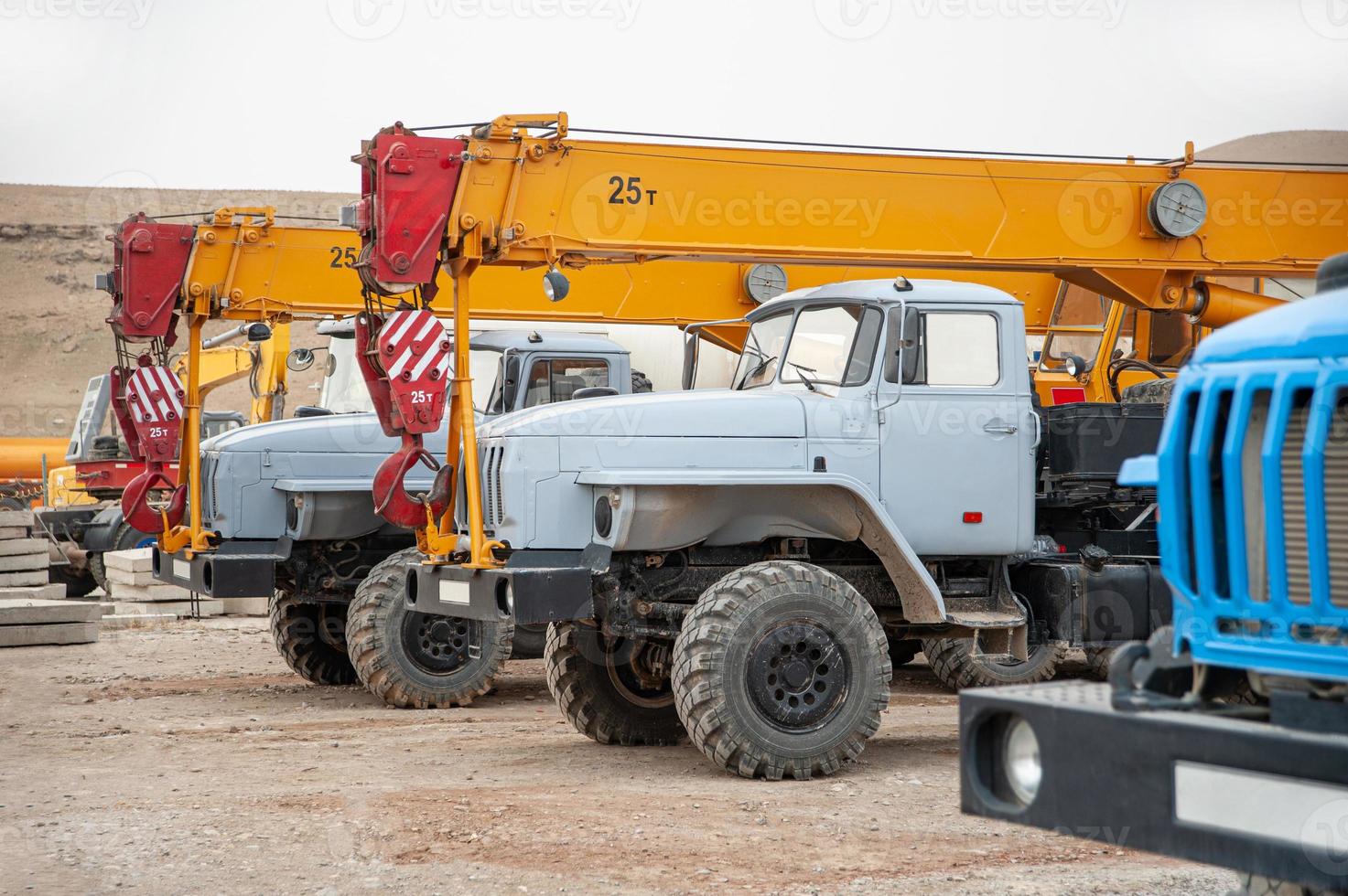 een rij van groot vrachtauto kranen en machines Bij een industrieel bouw plaats foto