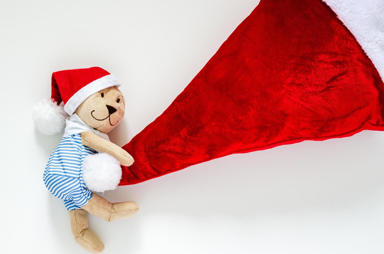 grijnzend teddy beer trekken de kerstman claus hoed voor Kerstmis achtergrond concept. foto